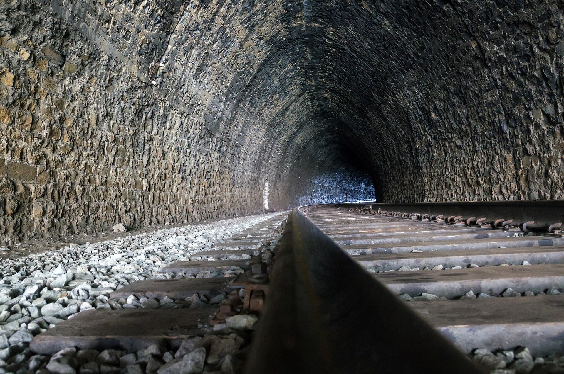 The lining and track inside a masonry railway tunnel, looking toward the portal