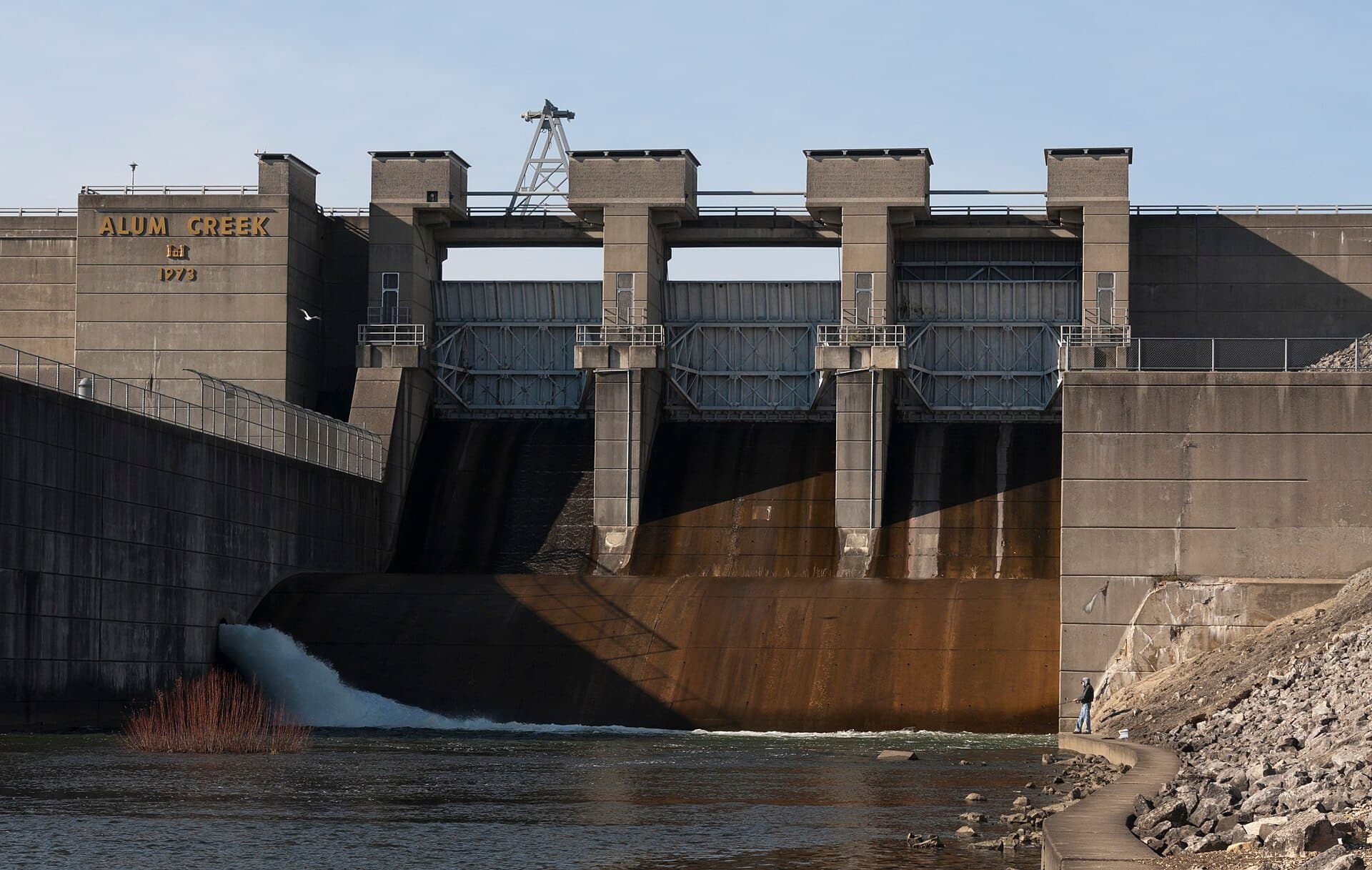 A gated concrete spillway at a dam, with water discharging