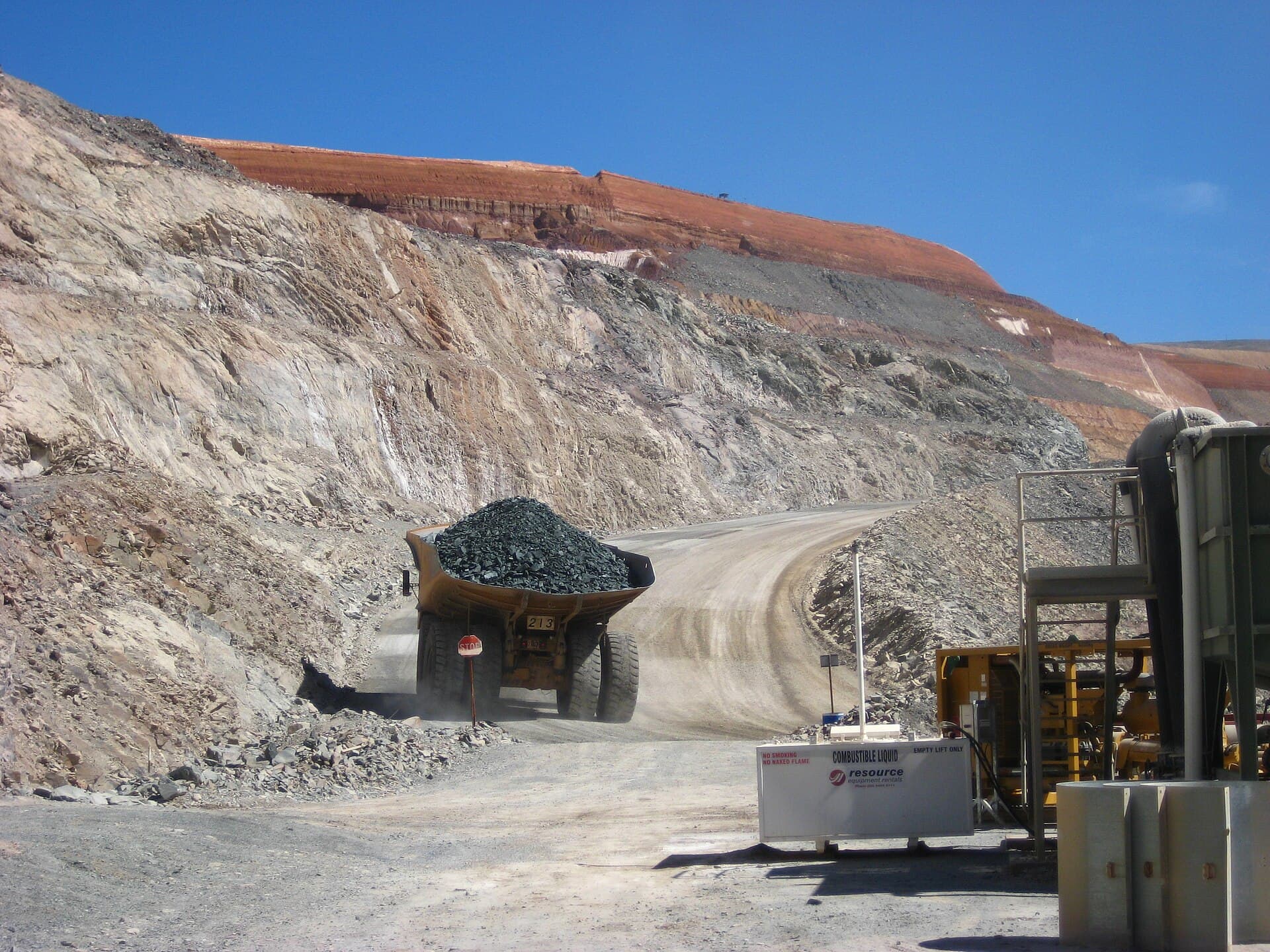 A haul truck on a bench road in an open pit, with the pit walls behind