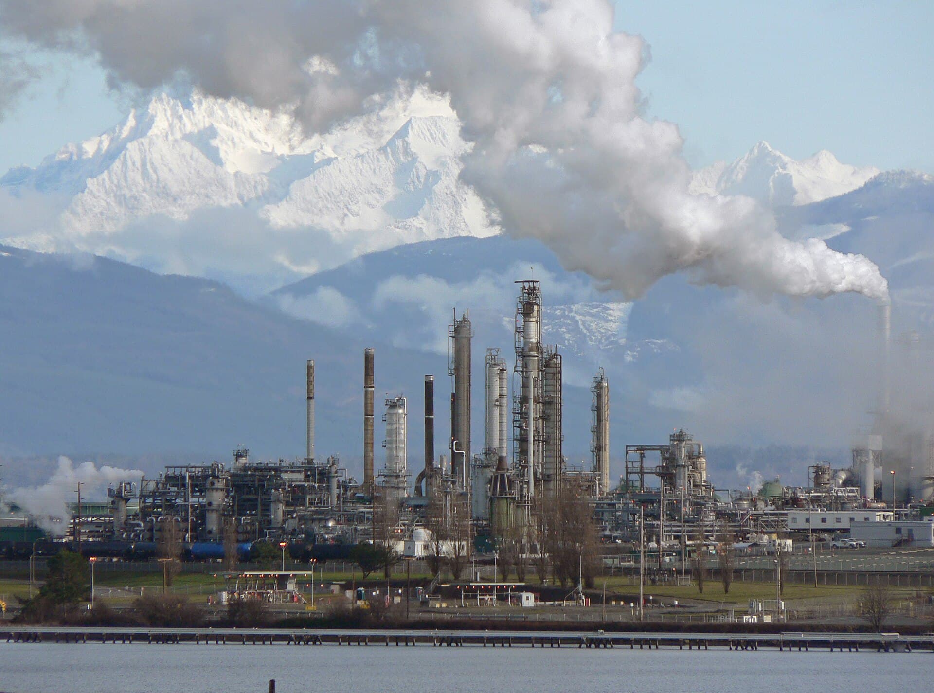 A refinery with distillation columns and stacks, mountains behind